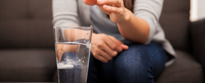 A woman dropping an antacid into a glass of water