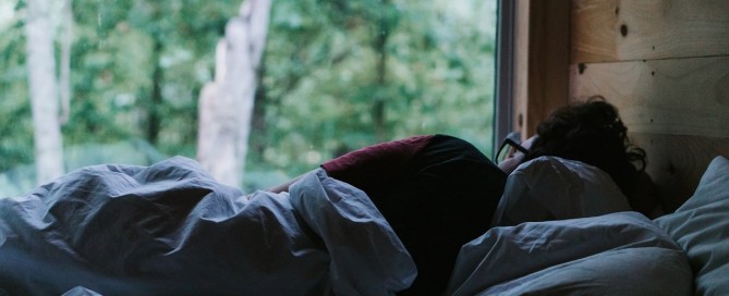 Man lying in bed looking out the window.