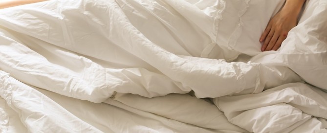 Woman trying to sleep during the warmer temperatures of summer.